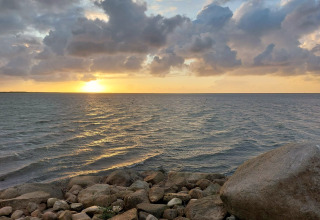 Coucher de soleil sur la mer et nuages vus depuis le gîte 6 personnes à Hemmet, Danemark, avec des rochers en premier plan.