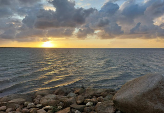 Atardecer sobre el mar con nubes dramáticas y rocas, visto desde casa de vacaciones en Hemmet, Dinamarca.