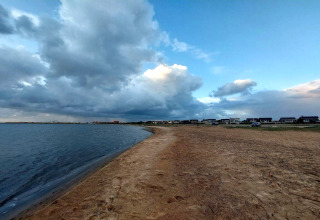 Skyet himmel over strand og hytter ved '6 personers feriehus i Hemmet', Danmark, tæt på vandet.