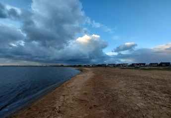 Skyet himmel over strand og hytter ved '6 personers feriehus i Hemmet', Danmark, tæt på vandet.