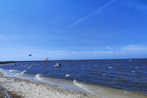 Strandzicht vanuit het 6-persoons vakantiehuis in Hemmet, Denemarken, met kitesurfers onder blauwe lucht