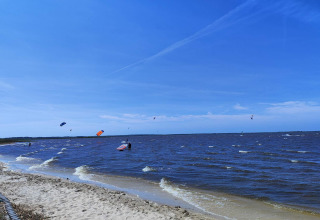Strandansicht vom 6-Personen-Ferienhaus in Hemmet, Dänemark mit Kitesurfern und blauem Himmel