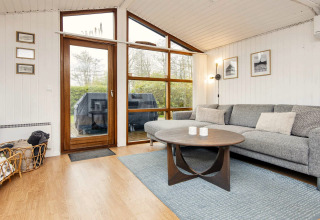 Salon moderne d'une maison de vacances à Hemmet, Danemark, avec grande fenêtre, canapé et table en bois.