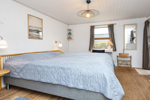 Lichte slaapkamer met tweepersoonsbed, bureau en raam in een 6-persoons vakantiehuis in Hemmet, Denemarken.