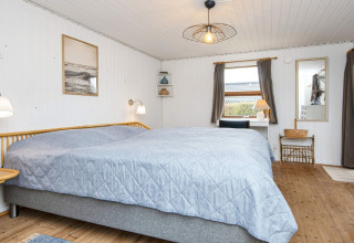 Lichte slaapkamer met tweepersoonsbed, bureau en raam in een 6-persoons vakantiehuis in Hemmet, Denemarken.