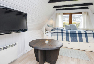 Zona giorno accogliente in una casa vacanze a Hemmet, Danimarca, con TV, tavolo tondo e letto-divano.