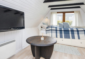 Zona giorno accogliente in una casa vacanze a Hemmet, Danimarca, con TV, tavolo tondo e letto-divano.