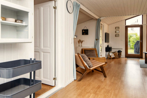 Salon lumineux d’une maison de vacances à Hemmet, Danemark, avec parquet et vue sur le jardin.