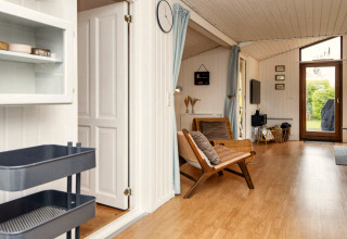 Salon lumineux d’une maison de vacances à Hemmet, Danemark, avec parquet et vue sur le jardin.