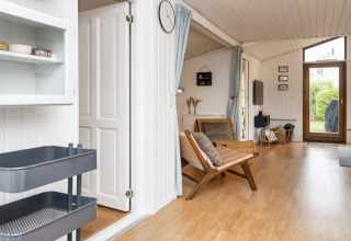 Lichte leefruimte in vakantiehuis in Hemmet, Denemarken, met houten vloer en zicht op tuin.