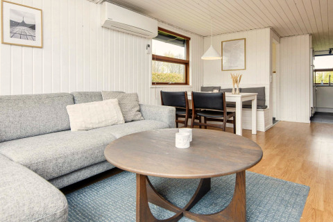 Lys og moderne stue i en feriebolig i Hemmet, Danmark, med sofa, sofabord og spiseplads.