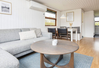 Heldere, moderne woonkamer in een vakantiehuisje in Hemmet, Denemarken, met sofa en eetgedeelte.