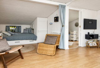 Lichte leefruimte in vakantiewoning in Hemmet, Denemarken, met bed, zitruimte en televisie.