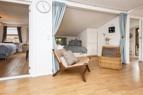 Sala de estar con paneles de madera blancos y acceso a dormitorios en casa de vacaciones en Hemmet, Dinamarca.