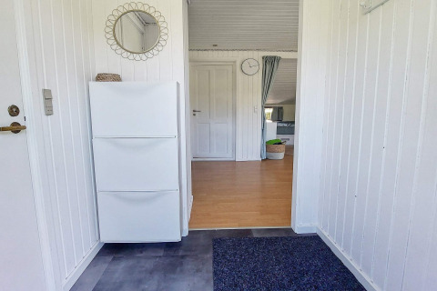 Entrée d'une maison de vacances à Hemmet, Danemark, avec murs blancs, armoire à chaussures et miroir rond.