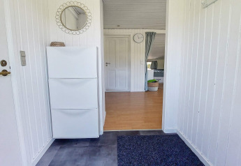 Entree van een vakantiehuis in Hemmet, Denemarken met witte muren, schoenenkast en ronde spiegel.