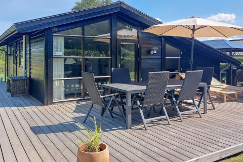 Terras van 6-persoons vakantiewoning in Hemmet, Denemarken, met tuinset en grote parasol.