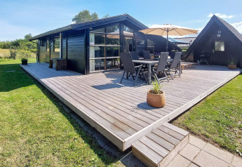 Buitenterras bij een 6-persoons vakantiehuis in Hemmet, Denemarken, met tuinmeubels en parasol.