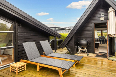 Terrasse extérieure du gîte 6 personnes à Hemmet, Danemark, avec transats et barbecue sur le pont en bois.