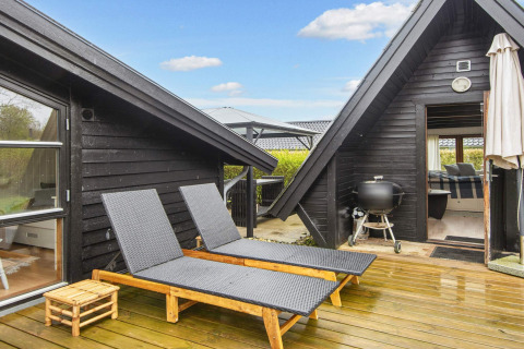 Terrasse eines 6-Personen-Ferienhauses in Hemmet, Dänemark, mit Sonnenliegen und Grill auf Holzdeck.