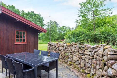 Buitenzitje van 6-persoons vakantiehuis in Roslev, Denemarken met stenen muur en houten bijgebouw.