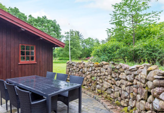 Terrasse am 6-Personen-Ferienhaus in Roslev, Dänemark, mit Steingartenmauer und Holzwand.