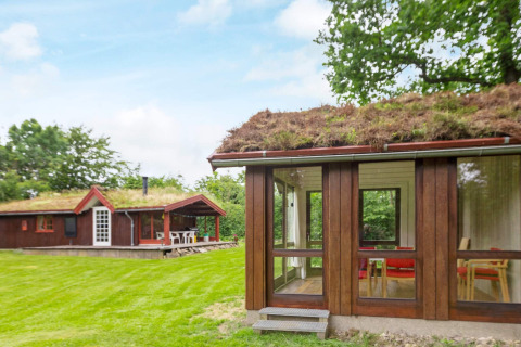 Ferienhaus mit Grasdach in Roslev, Dänemark, moderne Fenster und grüne Rasenfläche im Sommer.