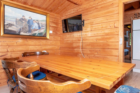 Essbereich mit Holzwänden, Gemälde, Wandfernseher, Holztisch und Stühlen in einer Lodge in Roslev, Dänemark.