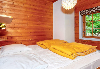 Slaapkamer met houten wanden, geel beddengoed en raam in een vakantiehuis in Roslev, Denemarken.
