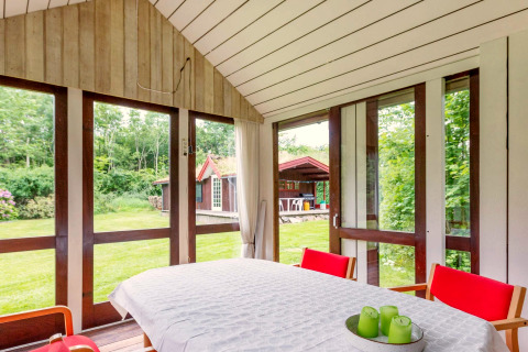 Salle à manger lumineuse dans une maison de vacances à Roslev, Danemark, avec vue sur le jardin.