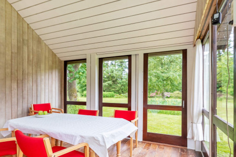 Casa vacanza luminosa a Roslev, Danimarca, sala da pranzo con sedie rosse e vista sul giardino verde.