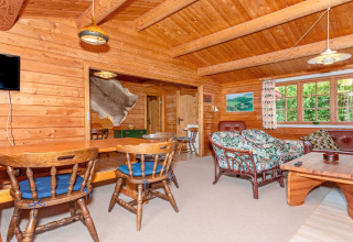Gemütliches Holz-Ferienhaus in Roslev, Dänemark, mit rustikalen Möbeln und großen Fenstern im Wohnraum.