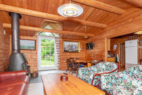 Gemütliches Wohnzimmer mit Holzverkleidung, Kamin und bunten Möbeln in einem Ferienhaus in Roslev, Dänemark.