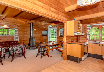 Hyggelig stue og køkken i træ i '6 personers feriehus i Roslev', Danmark, med brændeovn og store vinduer.
