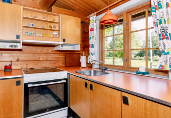 Cuisine en bois avec large fenêtre et plan de travail orange, dans « 6 person holiday home in Roslev », Danemark.