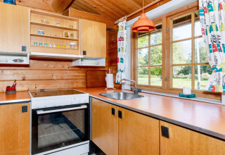 Keuken met houten afwerking en oranje aanrecht in '6 person holiday home in Roslev', Denemarken.