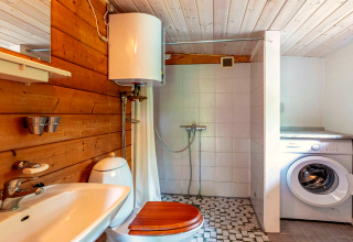 Salle de bain avec murs en bois et carrelage, douche, lave-linge et chauffe-eau à Roslev, Danemark.