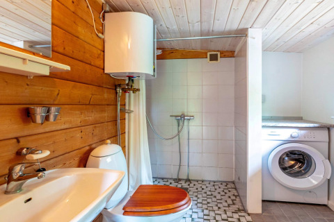 Badkamer met houten en betegelde muren, douche, wasmachine en boiler in Roslev, Denemarken.