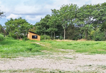 Kleines Ferienhaus zwischen Bäumen im Grünen bei einem 5-Sterne-Ferienhaus in Sydals, Dänemark.