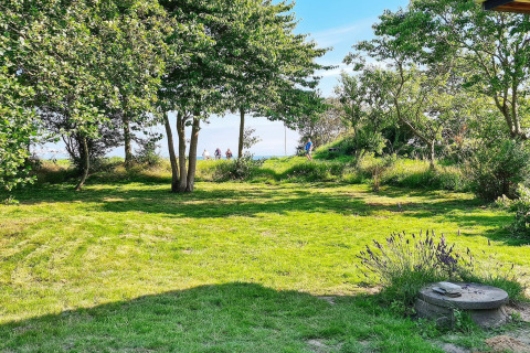 Grøn have med træer, buske og sollys ved feriehuset '5 star holiday home in Sydals', Danmark.