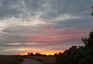 Smuk solnedgang over marker og vej nær 5 stjernet feriehus i Sydals, Danmark, med dramatiske skyer.