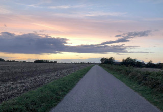 Coucher de soleil sur une route rurale près d'une maison de vacances 5 étoiles à Sydals, Danemark.