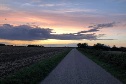 Cielo al atardecer sobre un camino rural junto a la casa de vacaciones 5 estrellas en Sydals, Dinamarca.