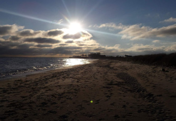 Sunset over a tranquil beach near the 5 star holiday home in Sydals, Denmark, with footprints in the sand.