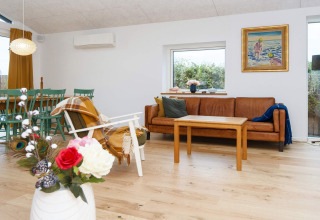 Moderne woonkamer in een 5-sterren vakantiehuis in Sydals, Denemarken, met bank, tafel en bloemen.