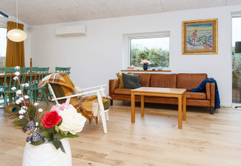 Modernes Wohnzimmer im 5-Sterne-Ferienhaus in Sydals, Dänemark, mit Sofa, Esstisch und Dekoration.