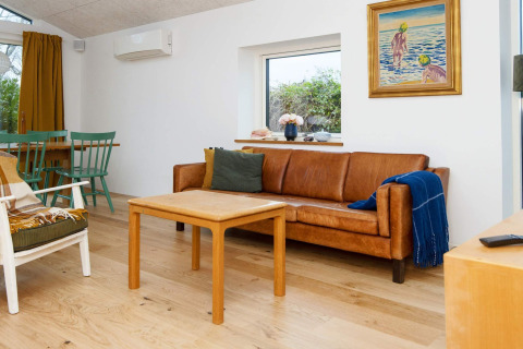Lichte woonkamer in vakantiewoning in Sydals, Denemarken, met lederen zetel en houten meubels.