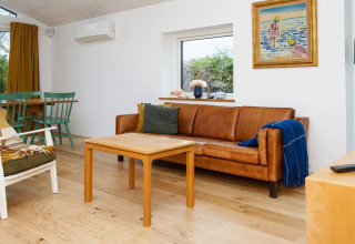 Lichte woonkamer in vakantiewoning in Sydals, Denemarken, met lederen zetel en houten meubels.