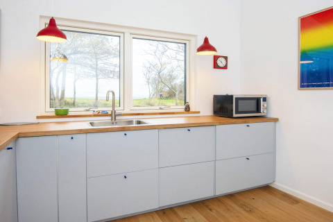 Moderne keuken in een 5-sterren vakantiehuis in Sydals, Denemarken, met rode lampen en grote ramen.