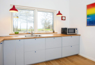 Moderne keuken in een 5-sterren vakantiehuis in Sydals, Denemarken, met rode lampen en groot raam.